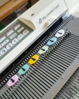 Needle markers placed on the needle bed of a Brother electronic knitting machine