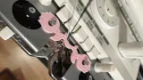 Pink floral plating yarn holder guiding two yarns on a Brother knitting machine